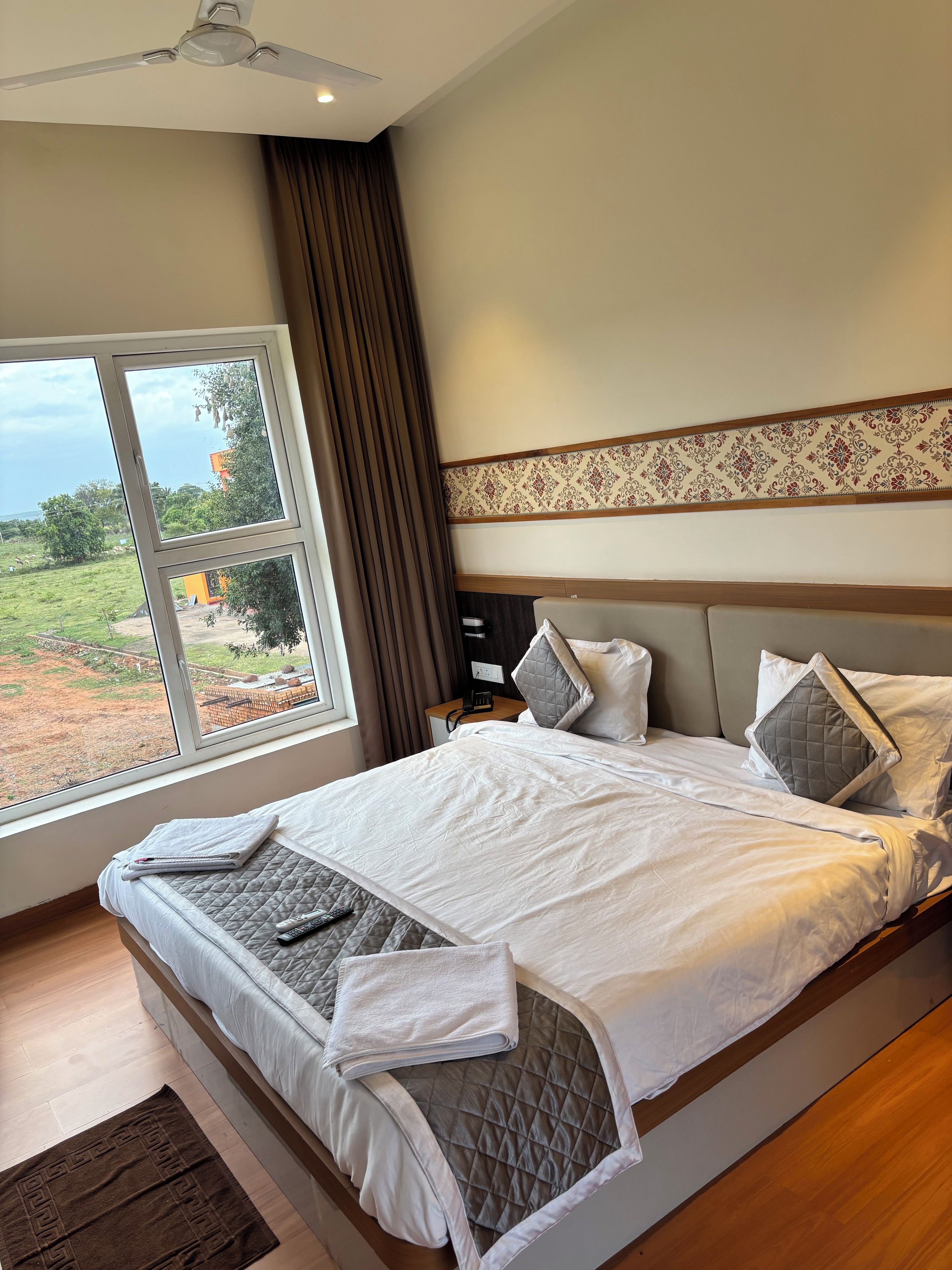 Una habitación de hotel con una cama grande, una mesita de noche, cortinas y vistas al exterior.
