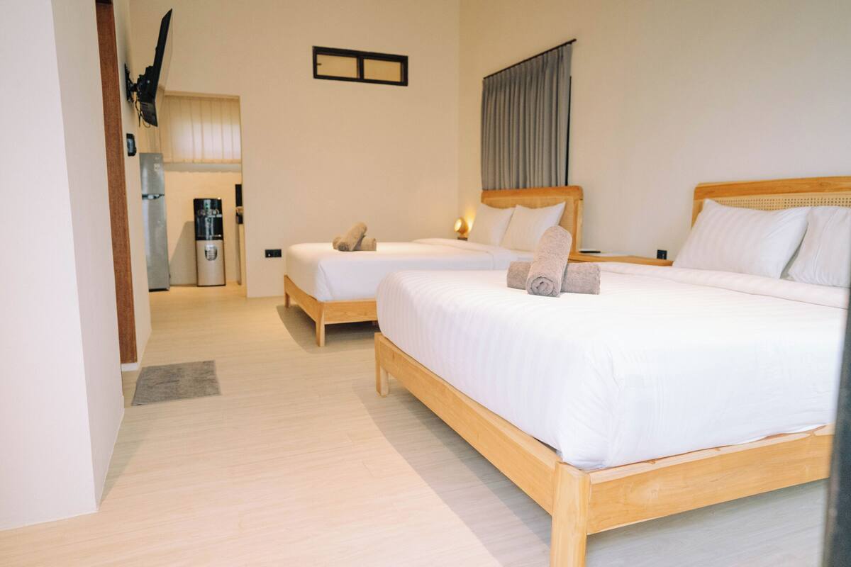 A hotel room with two single beds, a coffee machine, and a small kitchenette.