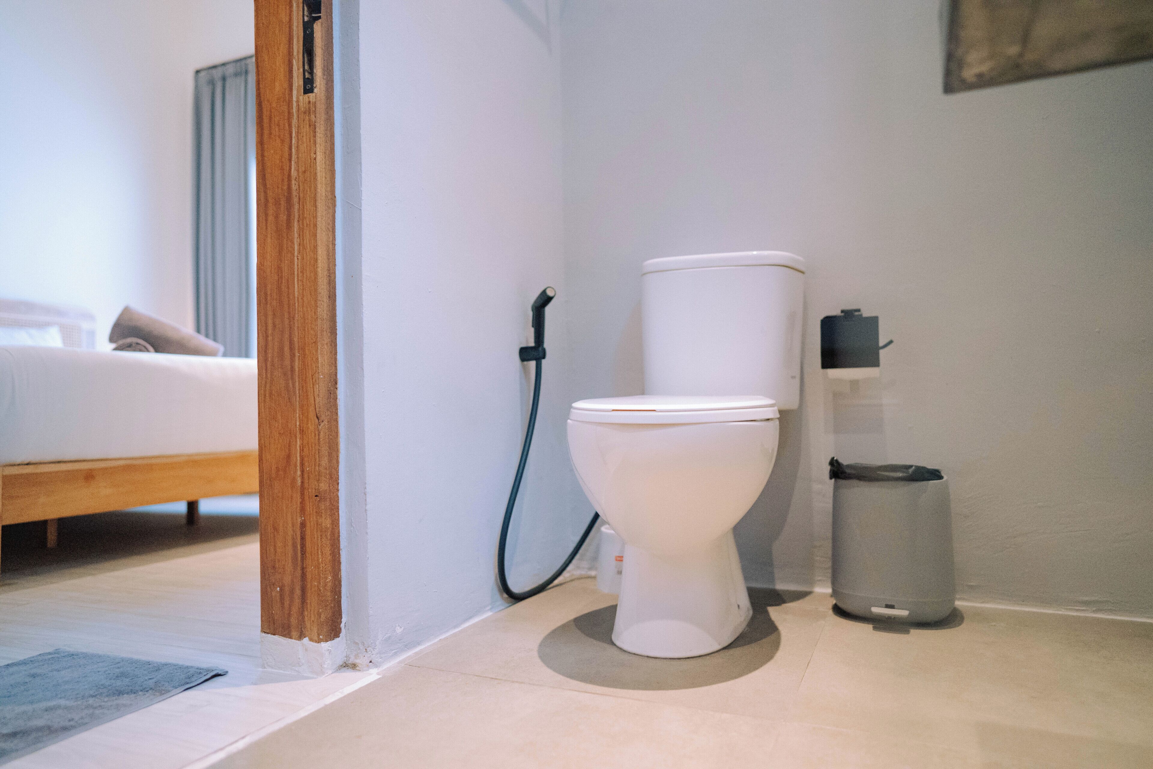 Une salle de bain équipée de toilettes, d’une poubelle et d’un tuyau de douche.