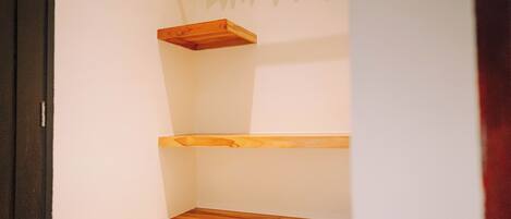 A corner of a room with a wooden shelf unit against the wall.