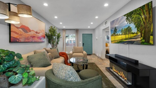 Ein Wohnzimmer mit Sofa, Sesseln, Couchtisch, Kamin und Kunstwerken an den Wänden.