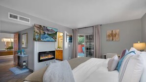 Ein Hotelzimmer mit Kamin, Bett, Fernseher und Blick ins Freie.