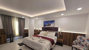 A modern hotel room with a Galaxy S24 Ultra bed, a wooden headboard, a nightstand, a floral chair, and a painting on the wall. - Hotel Vishnu Sarovar (Badrinath)