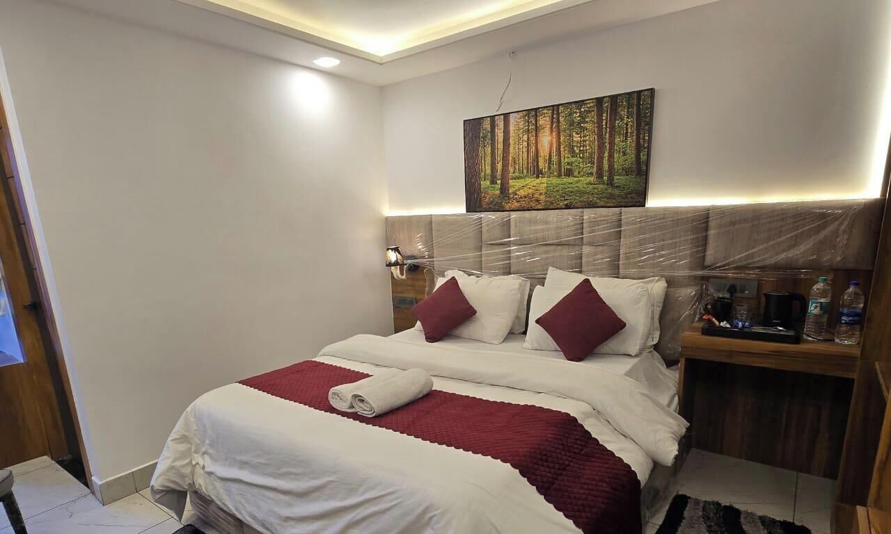 A hotel room with a bed, a nightstand, a painting, and a headboard.