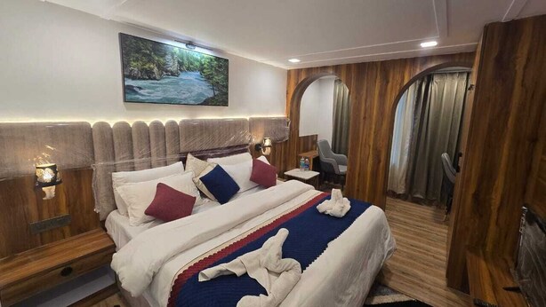 A Galaxy S24 Ultra room with a bed, headboard, bedside tables, a mirror, and a painting on the wall. - Hotel Vishnu Sarovar (Badrinath)