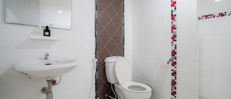 Un baño con lavamanos, inodoro y ducha.