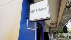 A sign labeled 'NP Place' mounted on a building with a blue and beige exterior. - NP Place Santitham (Chiang Mai)