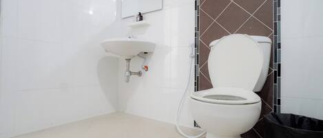 Baño con inodoro blanco, lavabo y espejo.