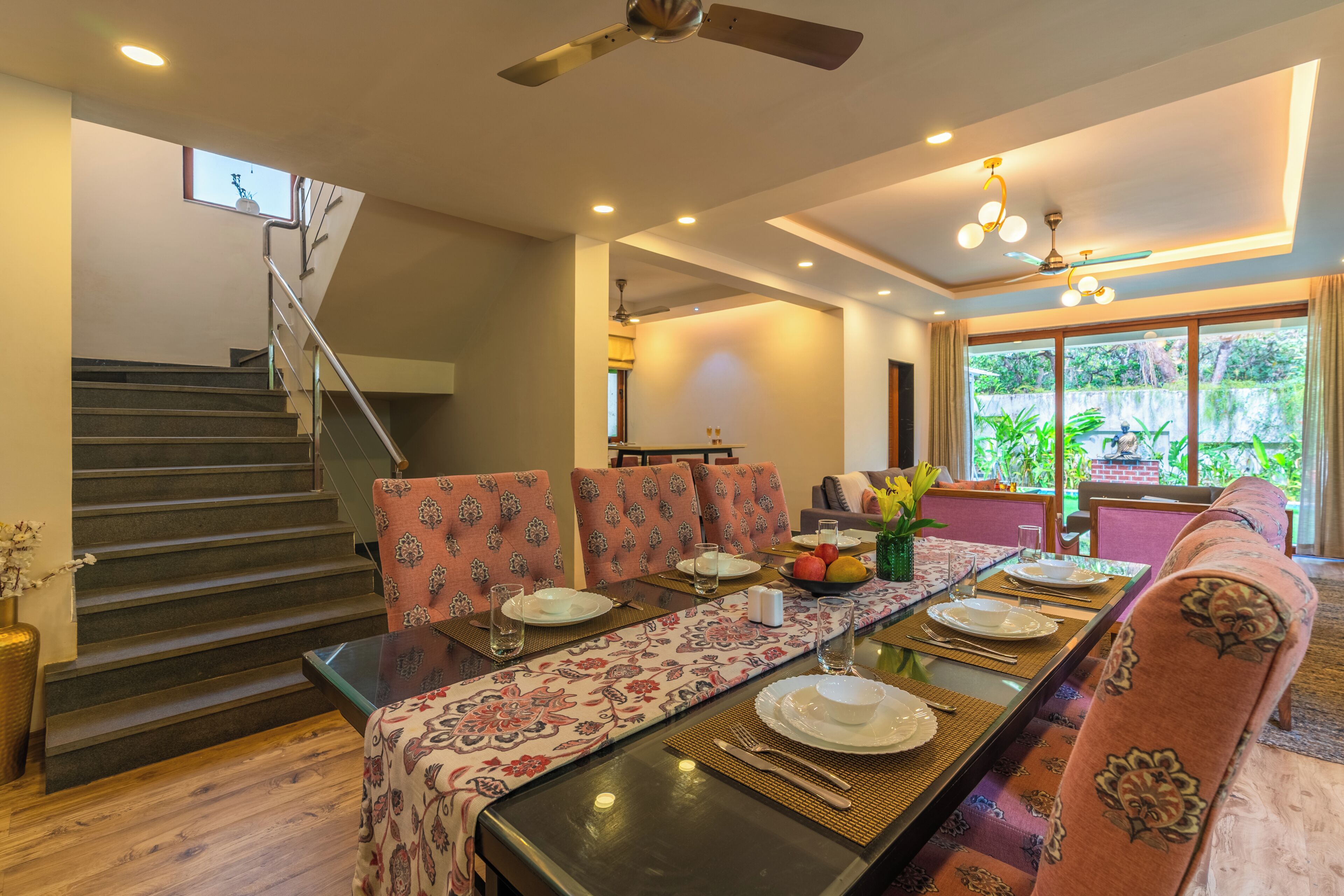 A dining area with a long table, chairs, and a staircase.