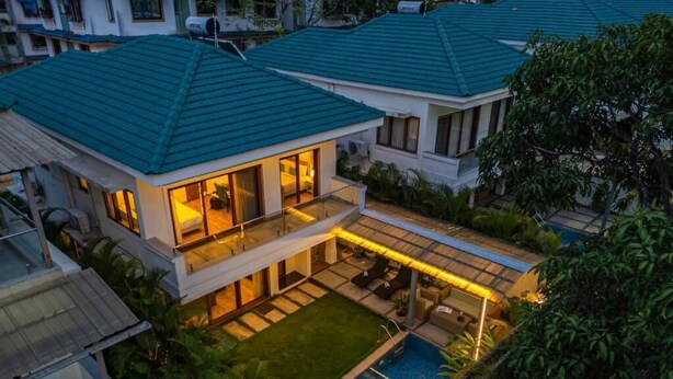 A modern two-story house with a swimming pool, a covered patio, and a well-maintained lawn. - ELIVAAS Azalea 3 BHK with Pvt Pool (Siolim)