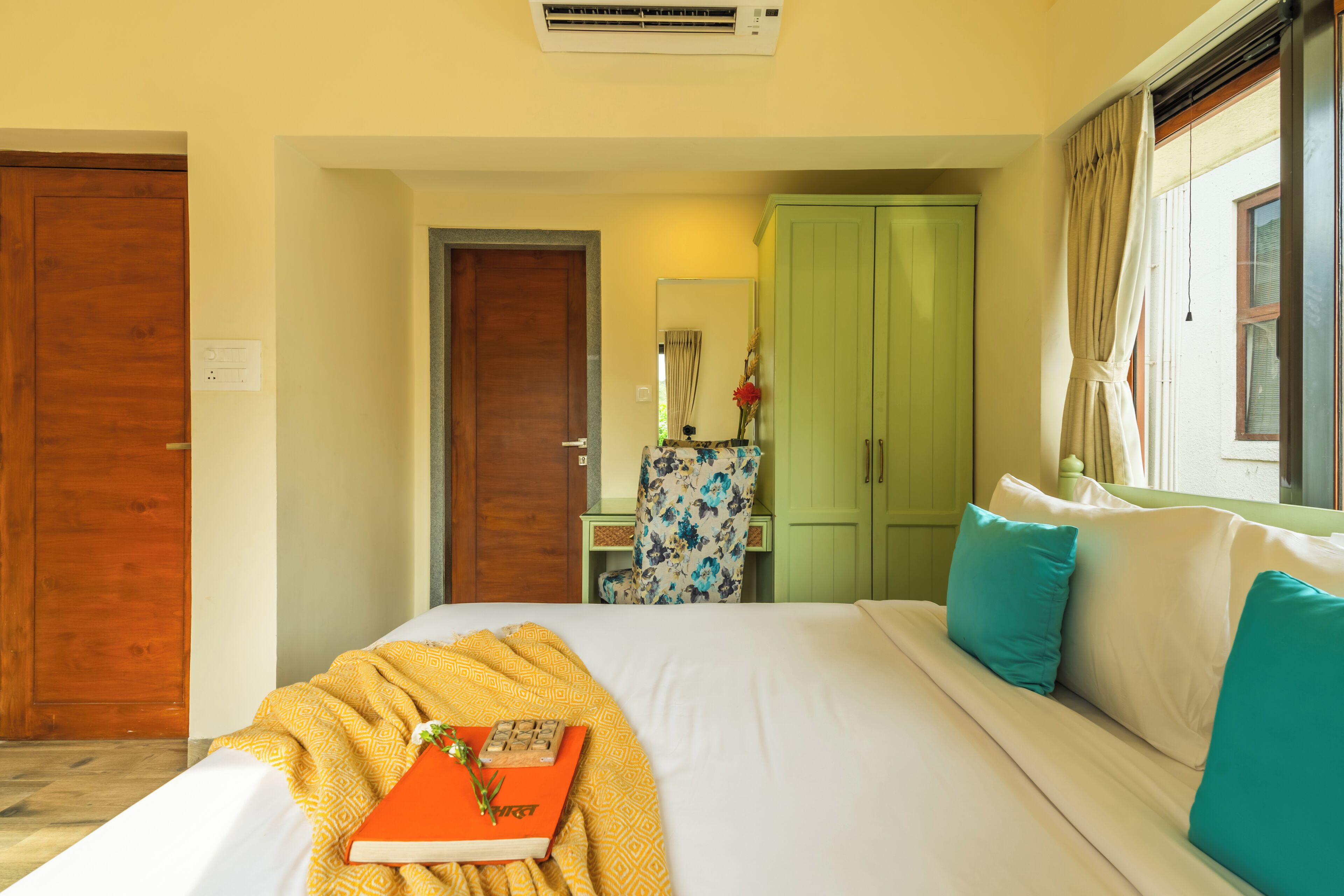 A hotel room with a bed, a desk, a wardrobe, and a window with curtains.