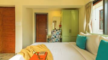 A hotel room with a bed, a desk, a wardrobe, and a window with curtains.