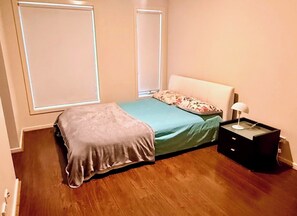 Une chambre à coucher avec un lit, une table de chevet et une fenêtre.