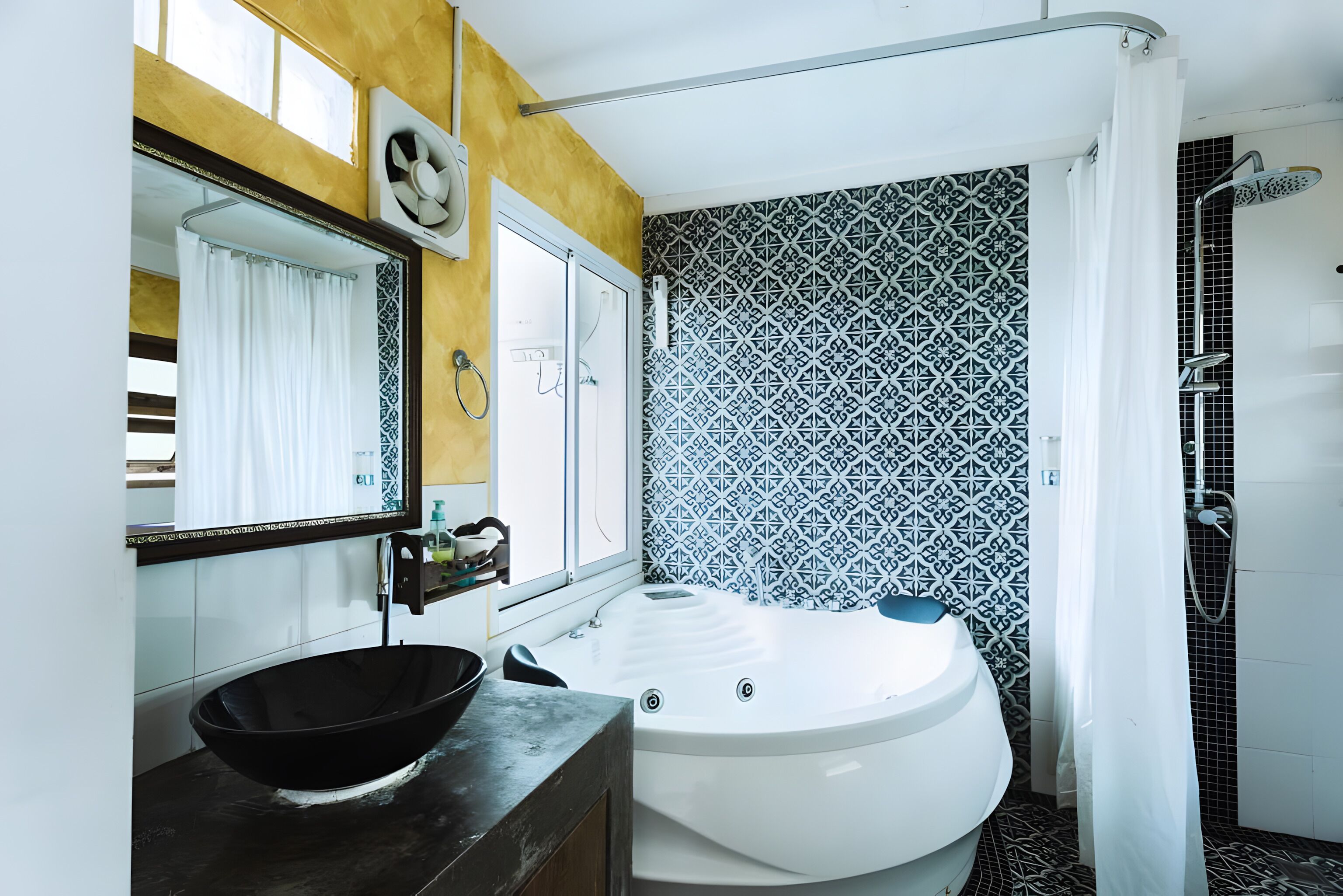 A bathroom with a black sink, a white bathtub, a shower, and patterned tiles.