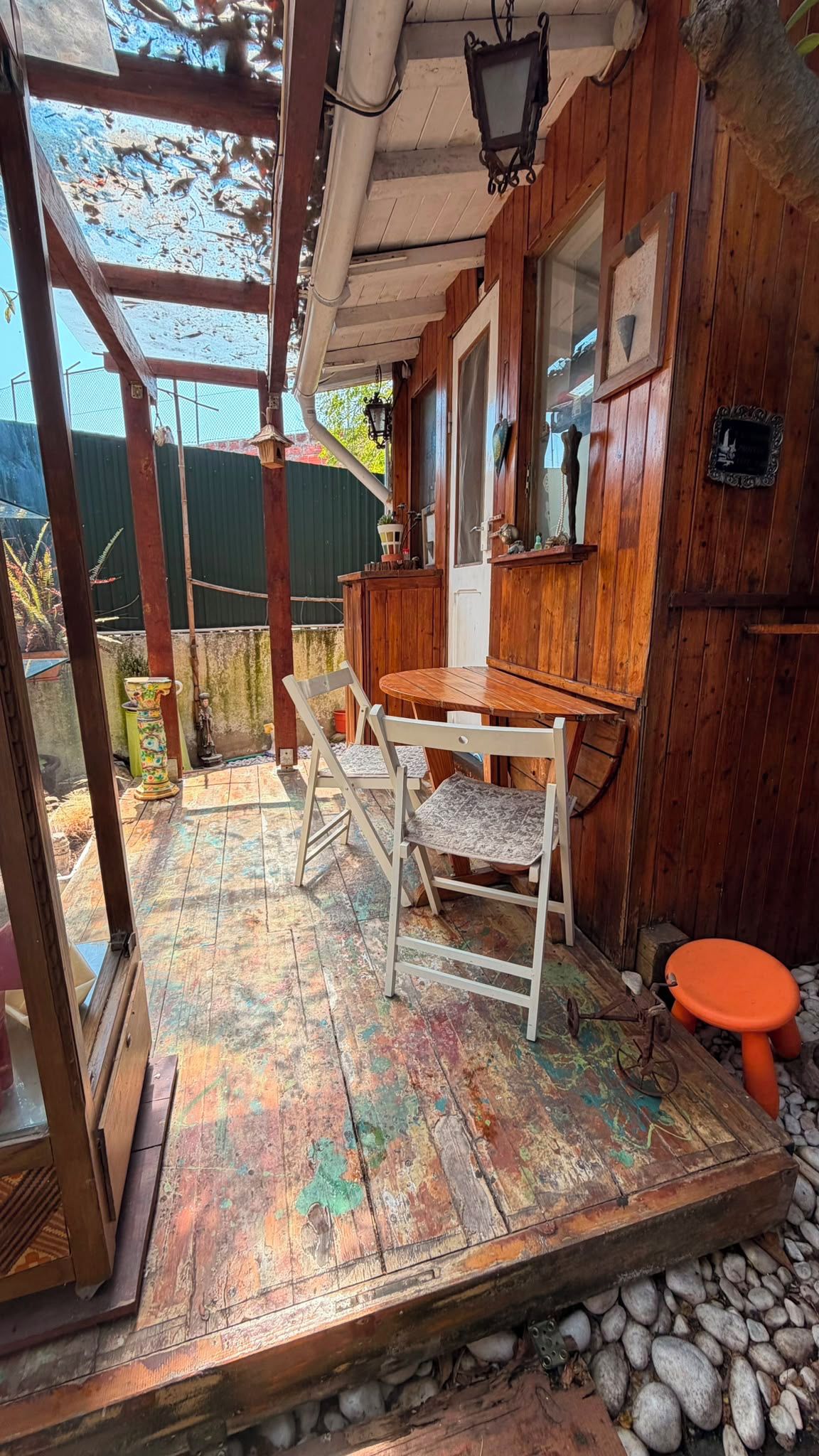Um quarto rústico de madeira com uma mesa e cadeiras de madeira, um banquinho pequeno e uma janela com vista para o exterior.