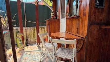 Um quarto rústico de madeira com uma mesa e cadeiras de madeira, um banquinho pequeno e uma janela com vista para o exterior.