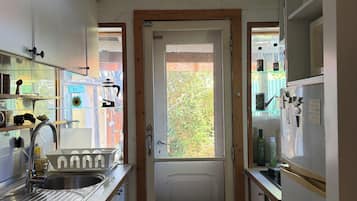 Une cuisine étroite avec une porte en bois, un évier en acier inoxydable et un réfrigérateur.