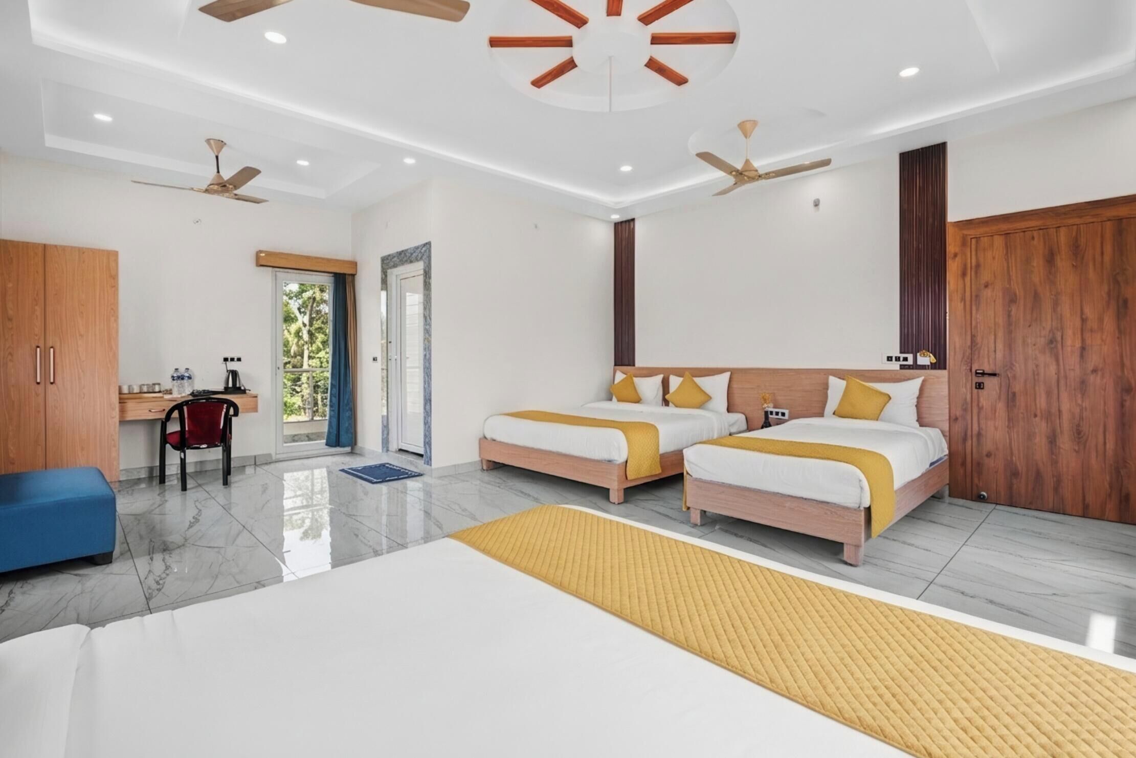 A modern hotel room with two beds, a desk, and a wardrobe.
