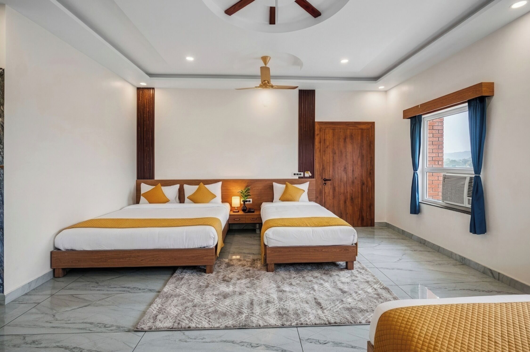 A double room with two beds, a ceiling fan, a window with curtains, and a door.