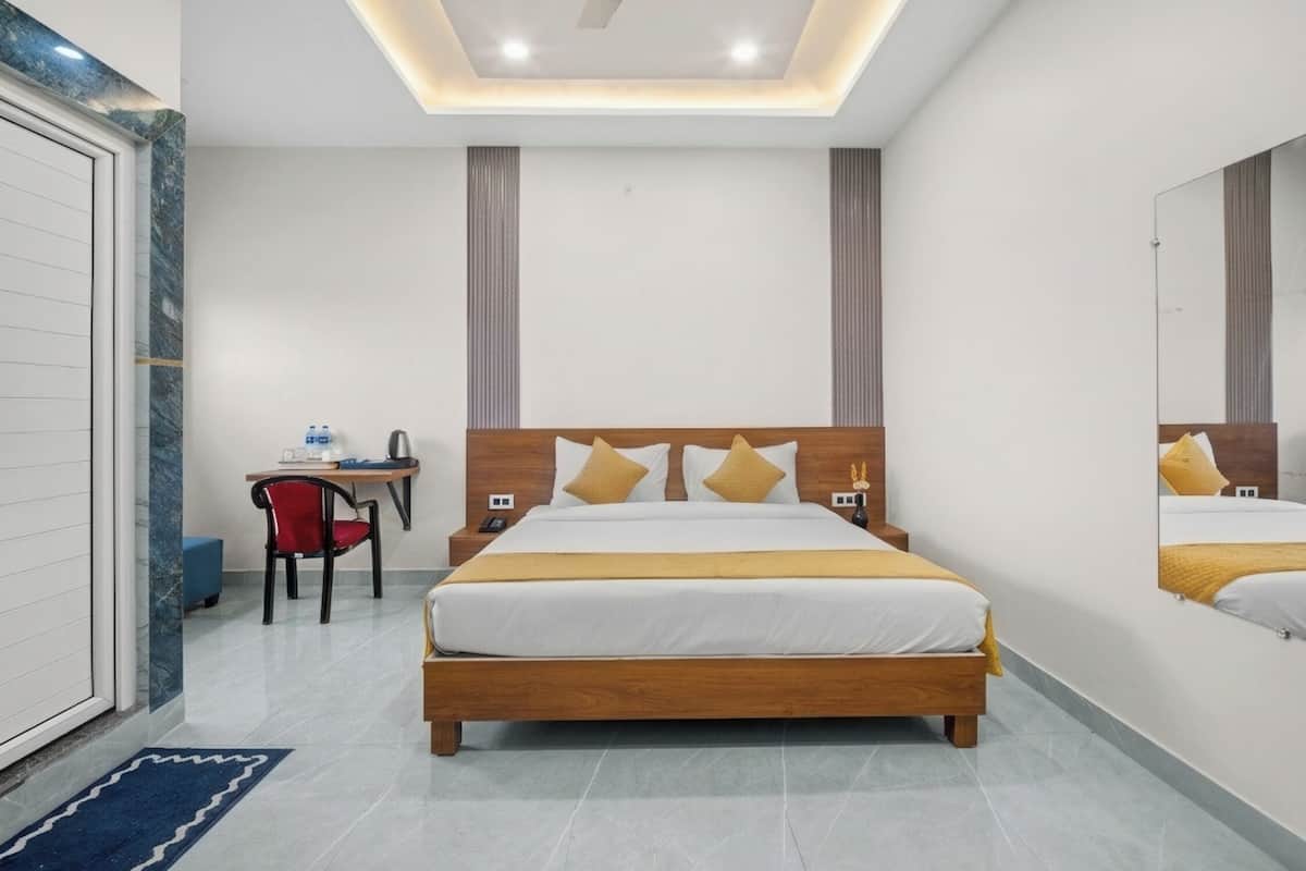 A hotel room with a large bed, bedside tables, a desk, and a chair.