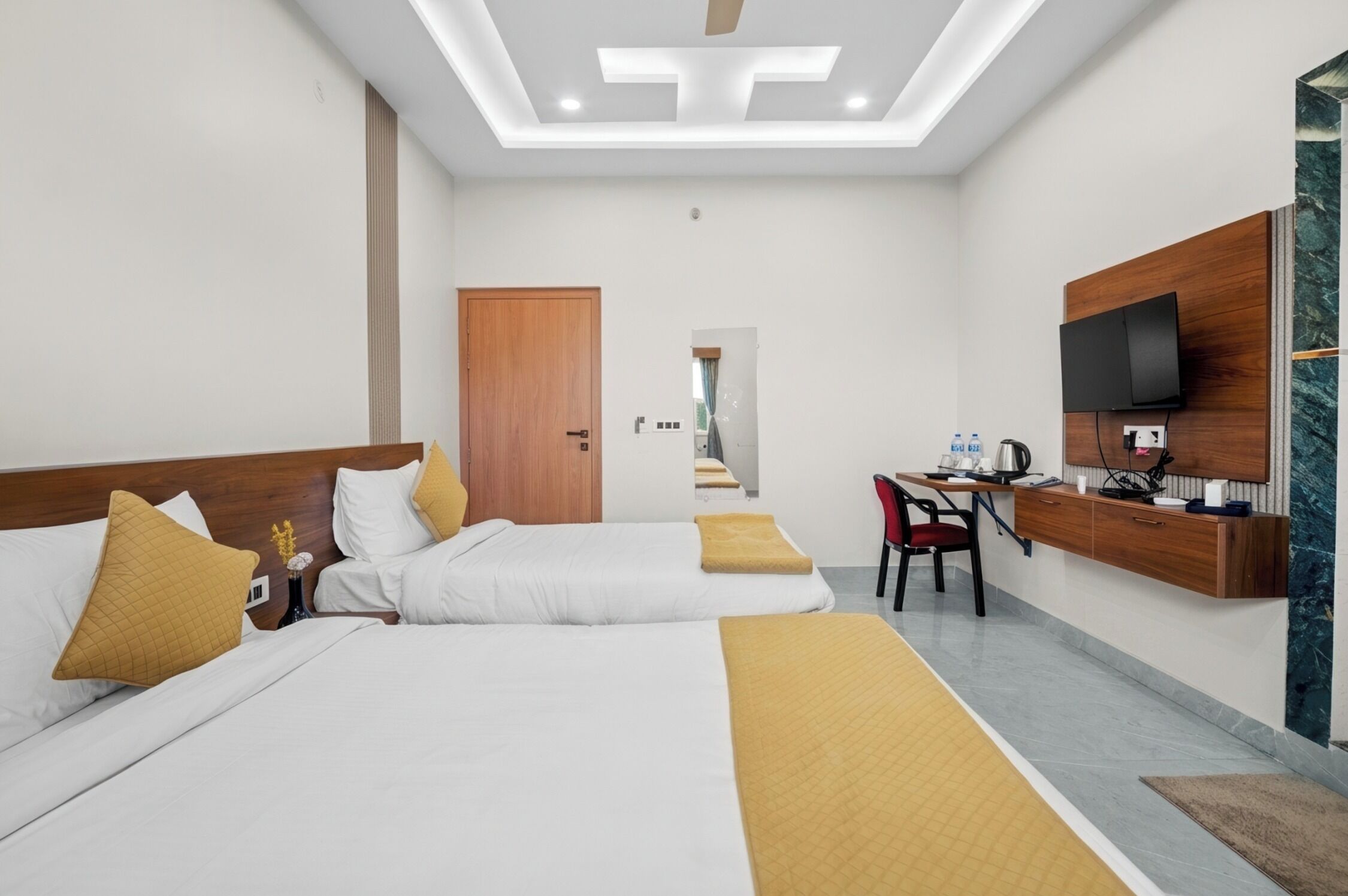 Habitación de hotel con dos camas, un escritorio, un televisor y un espejo.