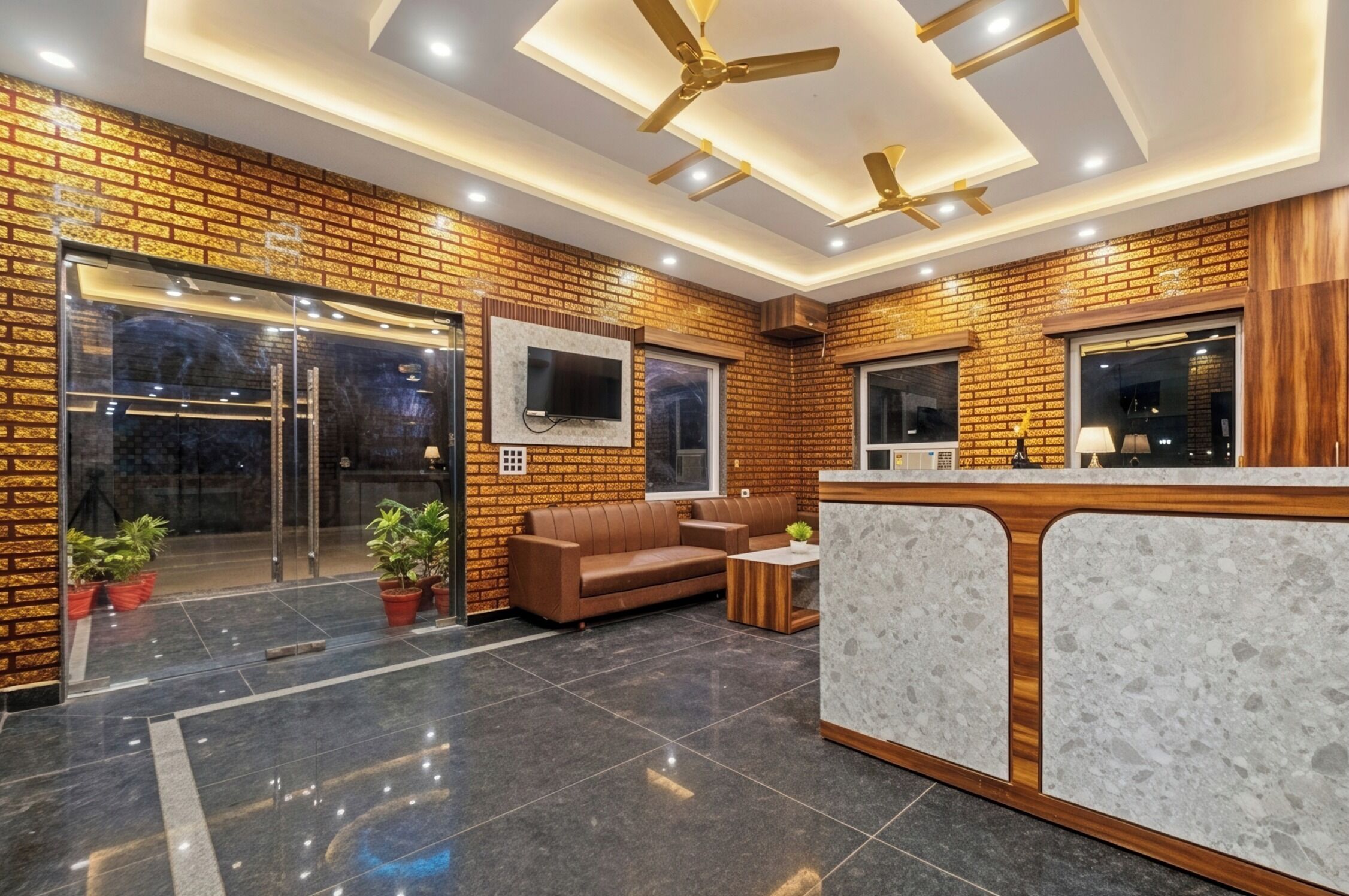 A reception area with a brick wall, a reception desk, a sofa, and ceiling fans.