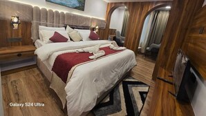 Een kamer met een Galaxy S24 Ultra, een bed, een houten hoofdbord, kunst aan de wand en een televisie.