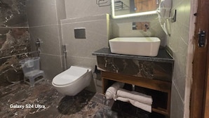 Een badkamer met een toilet, wastafel, douche en spiegel.