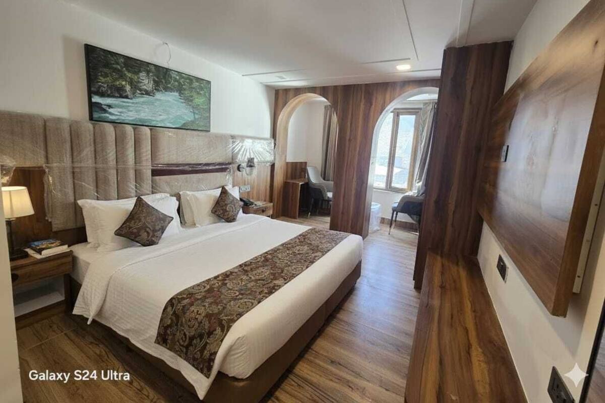 A Galaxy S24 Ultra room with a large bed, wooden flooring, a mounted TV, and a view of the outdoors.