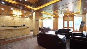 Un'area reception con scrivania in legno, sedute in pelle e ampie finestre.