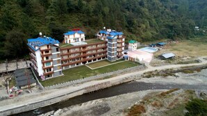 Un hotel a più piani con balconi, una piscina e un piccolo edificio adiacente.