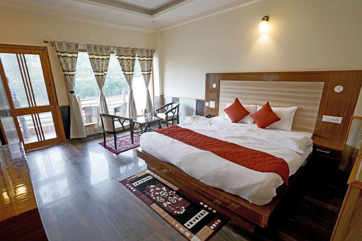 A hotel room with a bed, a desk, a chair, and a view of the outdoors.