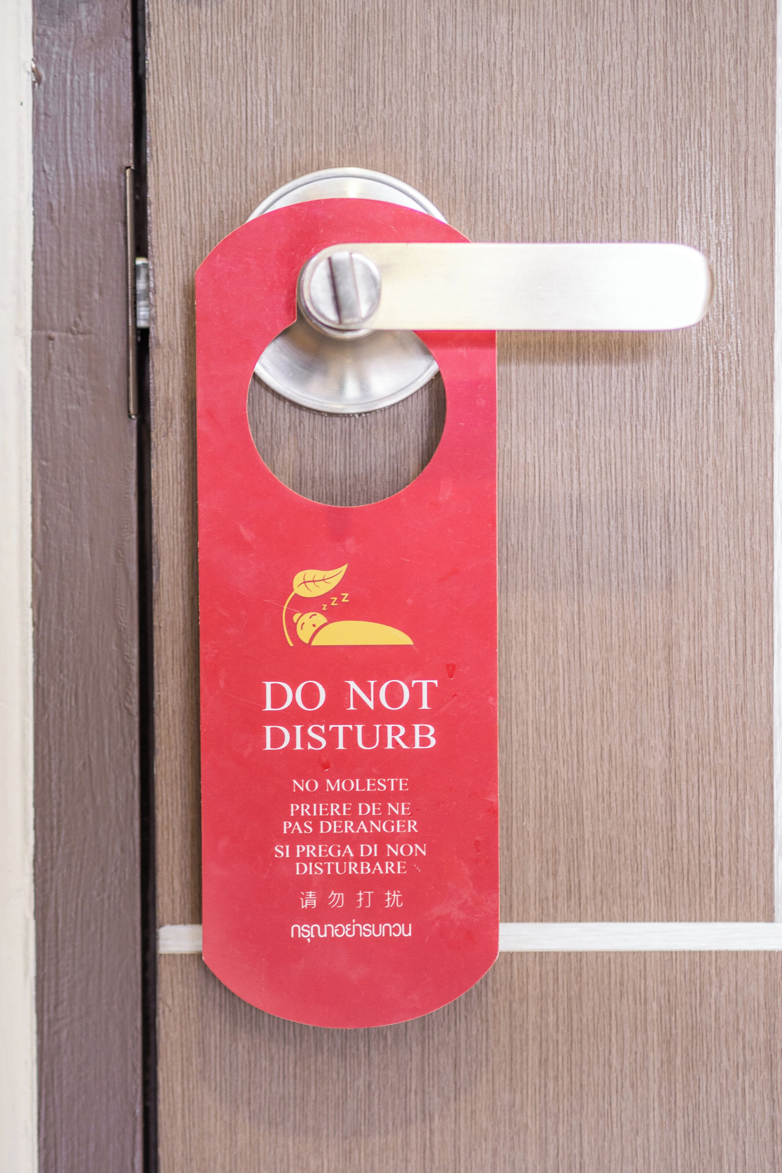 Un letrero rojo en la puerta con el símbolo de no molestar y texto en varios idiomas.