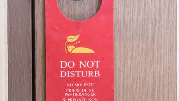 Un letrero rojo en la puerta con el símbolo de no molestar y texto en varios idiomas.