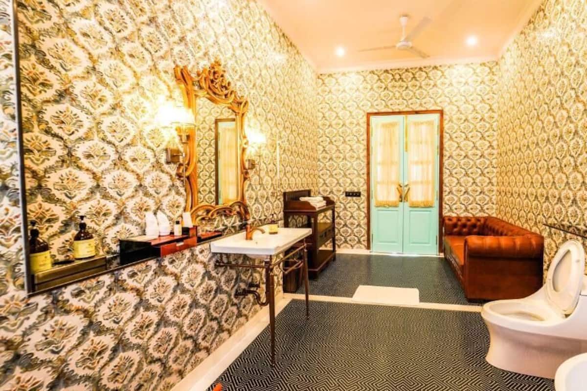 Une salle de bain avec un papier peint à motifs, des toilettes, un lavabo, un miroir et un ventilateur de plafond.