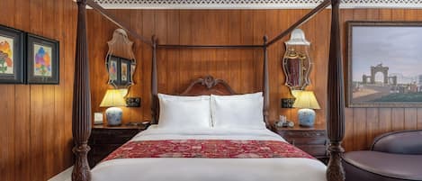 A four-poster bed with white linens, wooden headboard, and decorative lamps.