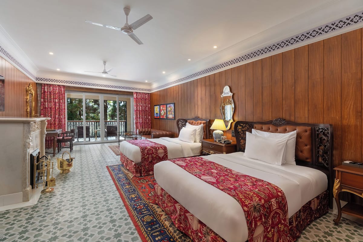 Une chambre d’hôtel avec deux lits, un balcon, une cheminée et une vue sur l’extérieur.