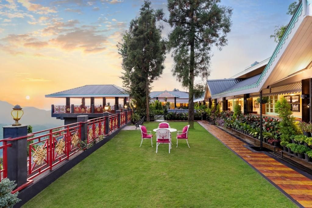 A hotel courtyard with a lawn, red railing, and a view of the sunset.