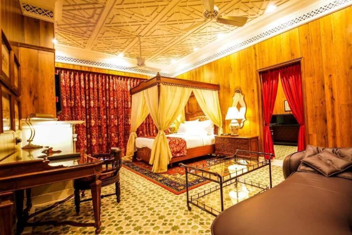 Une chambre de style traditionnel, dotée d’un lit à baldaquin, d’un bureau, d’un fauteuil de massage et d’un piano.
