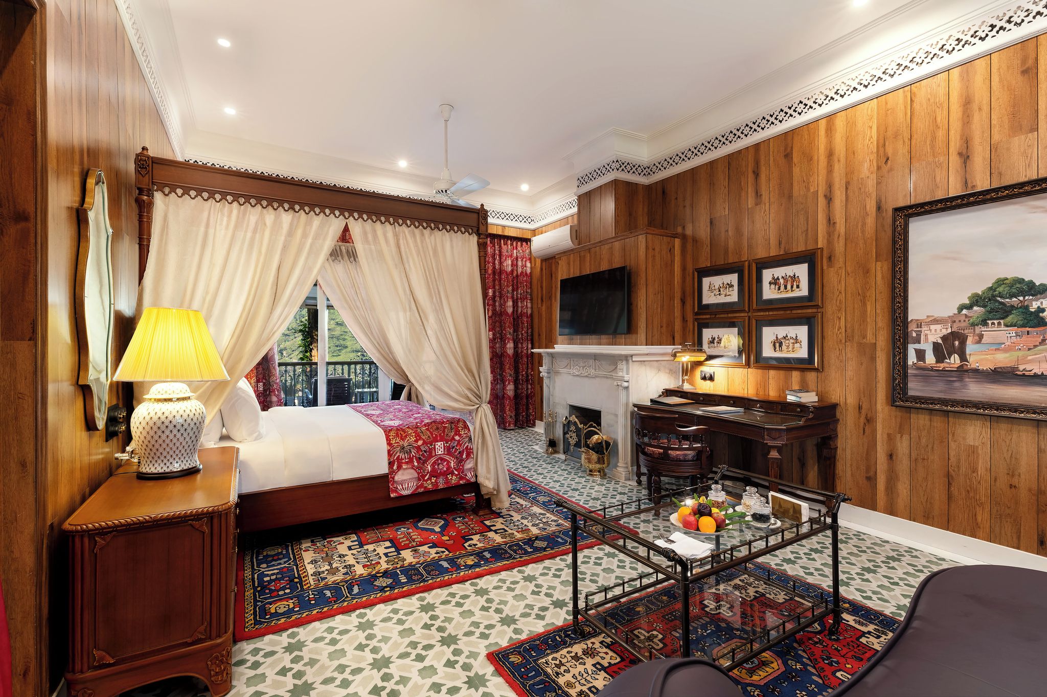 Un dormitorio con cama, escritorio, televisor y chimenea.