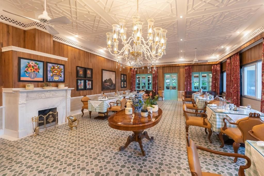 A dining area with multiple tables, a chandelier, and framed artwork on the walls.