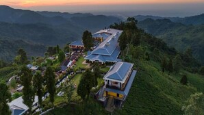 Un hôtel composé de plusieurs bâtiments situés sur une colline, entouré d’une végétation luxuriante et de montagnes.