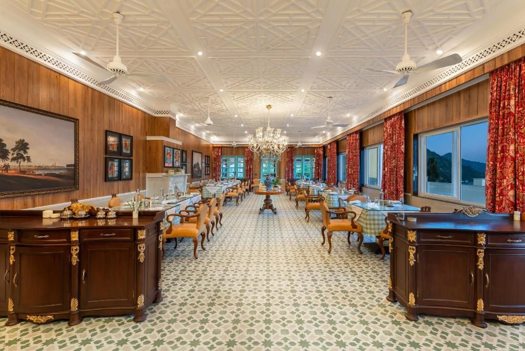 A spacious hotel lobby with a high ceiling, chandeliers, wooden paneling, and a central seating area.