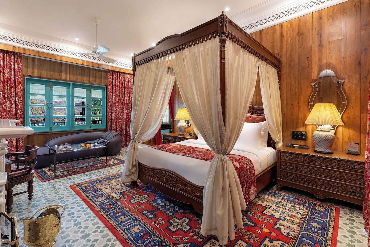 Un lit à baldaquin, un canapé, une table de chevet avec une lampe et un tapis à motifs.