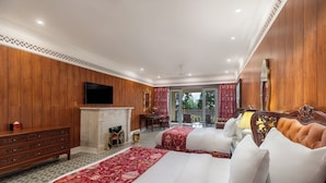 Een hotelkamer met twee bedden, een televisie, een open haard en een balkon met uitzicht.