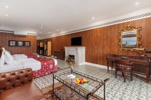 Ein Hotelzimmer mit Bett, einer Couch, einem Schreibtisch, einem Kamin und einem Spiegel.