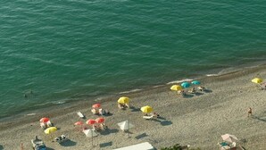 Vista aérea de una playa con sombrillas y tumbonas.