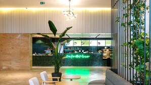 Un vestíbulo moderno con asientos, un letrero de neón, una zona de bar y una planta.