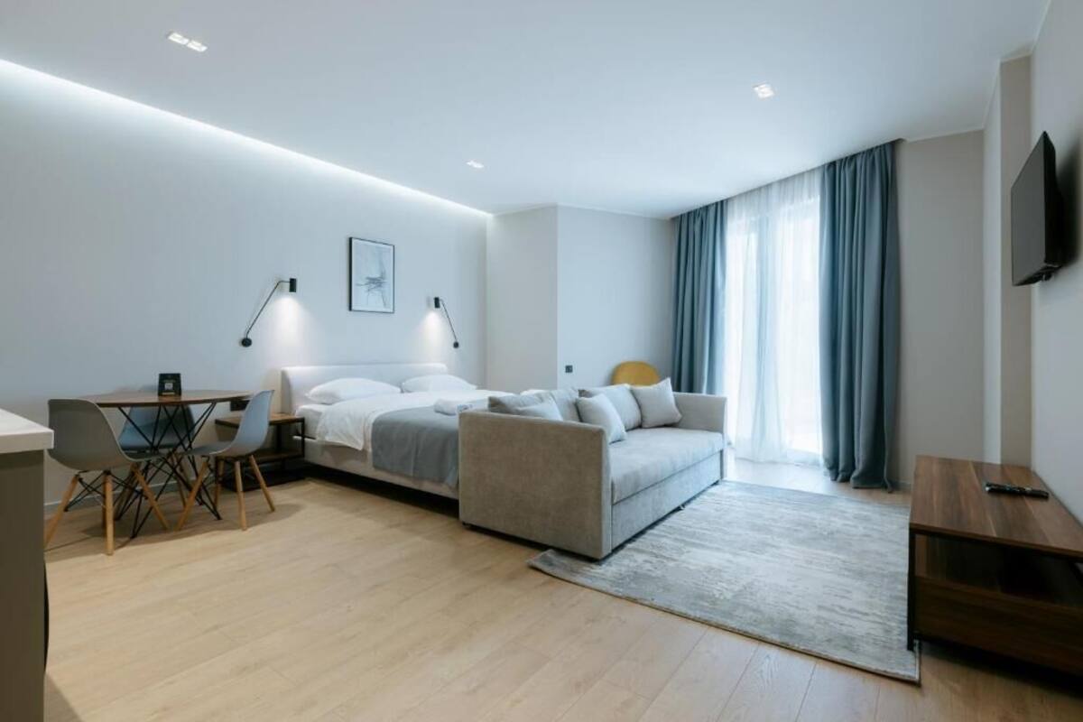 Een moderne hotelkamer met een bed, bureau, stoel, televisie en een raam met gordijnen.