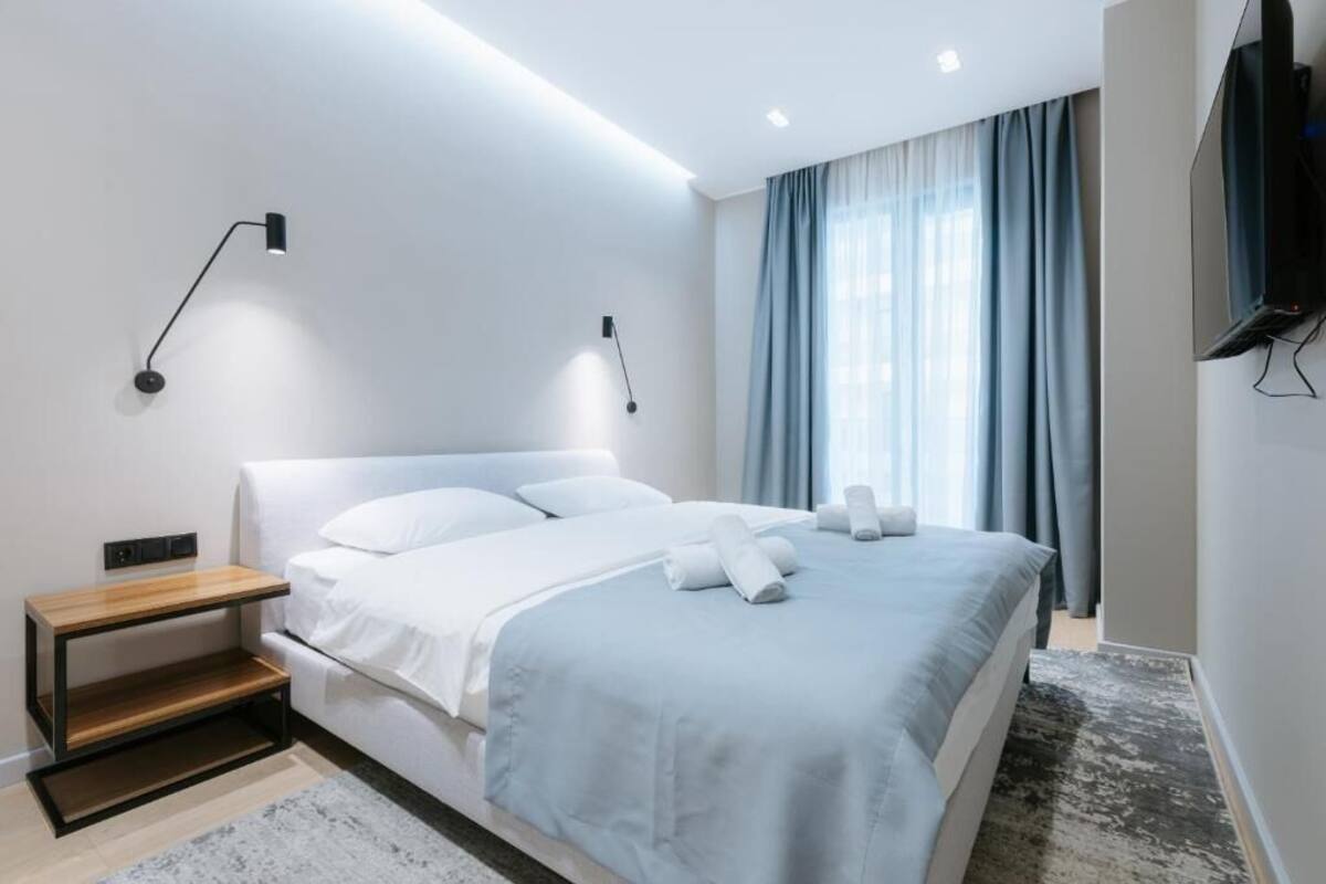 Een moderne hotelkamer met een bed, nachtkastjes, een televisie en een raam met gordijnen.